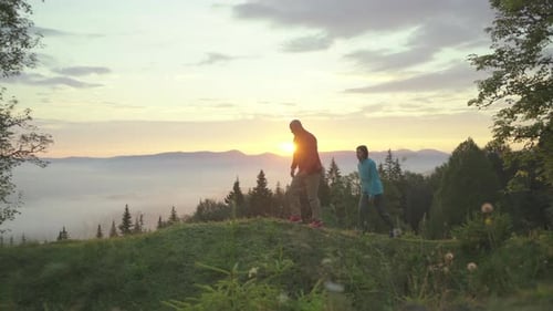 Man and Woman Walk on the Hill and Greet the Sunrise in Mountains. Happy Couple Enjoys Beautiful