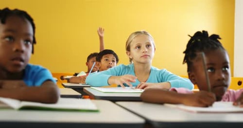 Crianças em idade escolar levantando a mão na sala