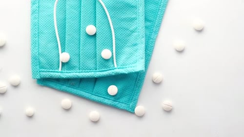 Close Up of Blue Surgical Masks and Medical Pills on Table