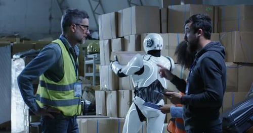 Warehouse Staff and Robot Standing by Boxes