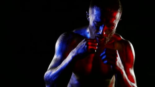 a Muscular Man with a Bare Torso and Golden Metallic Skin Fights with a Shadow on a Dark Background