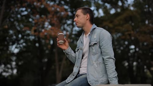 Man Drinks Coffee in an Urban Park