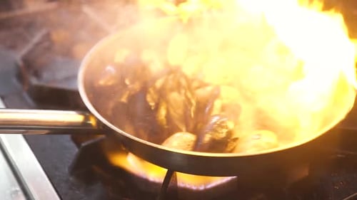 Remuer et fermer les moules et les pétoncles en feu à l'aide d'une poêle