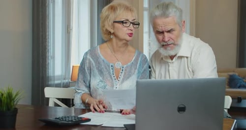 Mature Couple Discussing Finances with Laptop at Home
