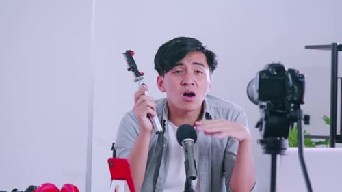 Jovem asiático vendendo aparelhos fotográficos nas redes sociais transmitindo ao vivo de sua casa.