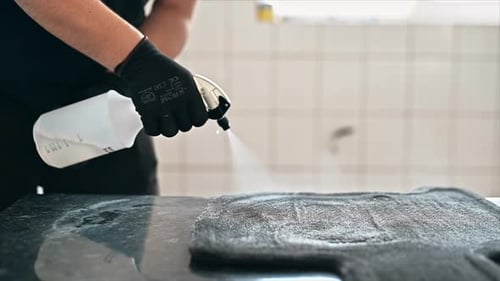 Working cleaner at car wash. Cleaning a carpet using a spray with chemical solution. Slow motion