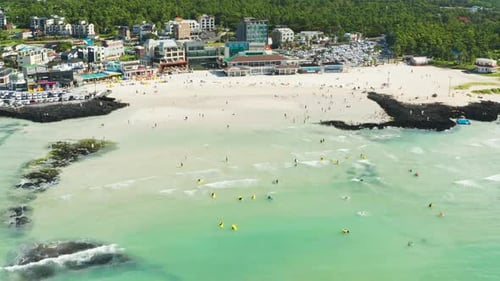 People enjoying summer vacation and wavy beach scenery. Jeju Island.