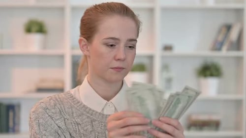 Portrait d'une jeune femme focalisée comptant des dollars