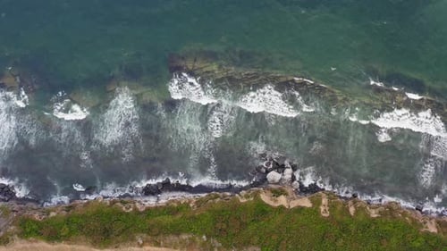 A View of the Ocean and Waves Crashing Against the Rocky Shore with White Foam