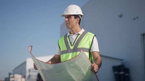 Thoughtful Professional Middle Eastern Engineer Architect Examining Blueprint Outdoors in Slow