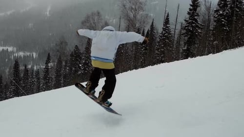 Zeitlupe eines männlichen Snowboarders, der auf einer Piste springt
