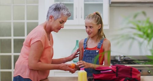 Woman Gives Child Orange Snack in Sunny Kitchen
