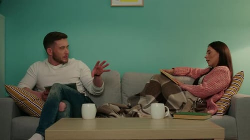 Couple Reading and Talking Together on Couch