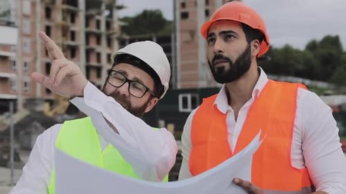 Construction Workers Reviewing Plans at Building Site