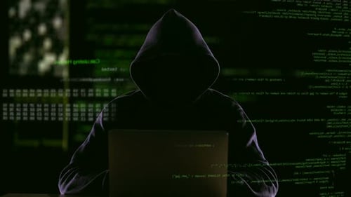 Hooded Figure Hacking Data at Night