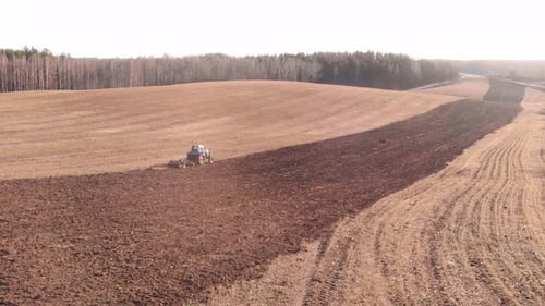 Moving tractor plows field.