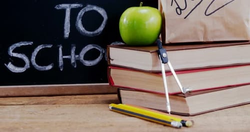 Apple and book with school supplies on table