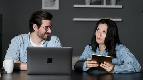 Couple looks at technology at dark home table