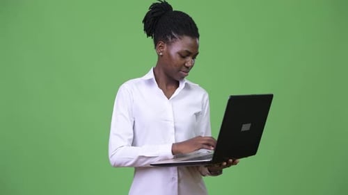Young Woman Typing on Laptop with Green Background