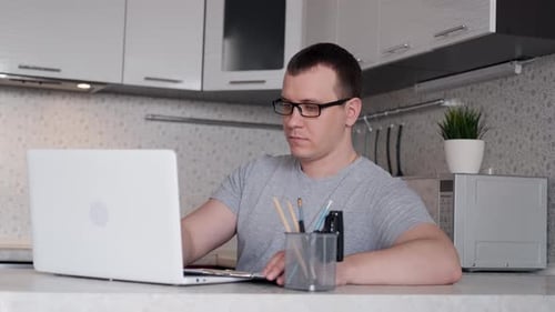 Man Working on Laptop in Home Kitchen