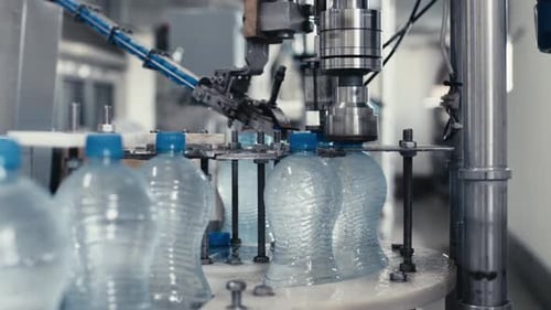 Wasser-Fabrik-Industriemaschine setzt Kappen auf Plastik-PET-Flaschen mit Wasser Nahaufnahme