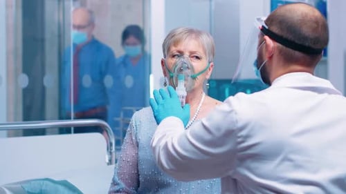 Doctor Adjusts Oxygen Mask on Senior Woman