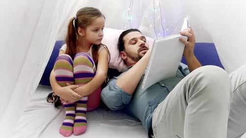Father Reads Book to Daughter in Cozy Room