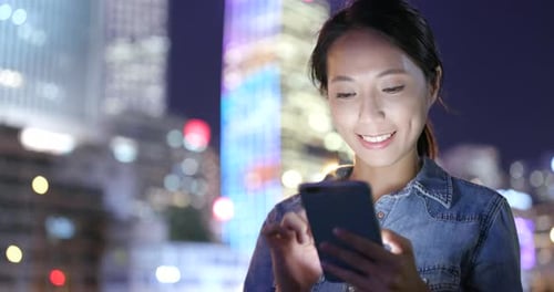 Woman use of smart phone in city at night