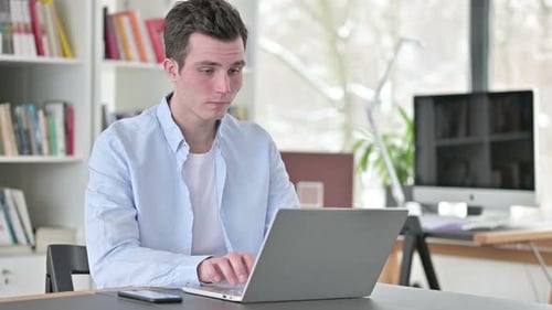 Young Adult Working on Laptop in Office Setting