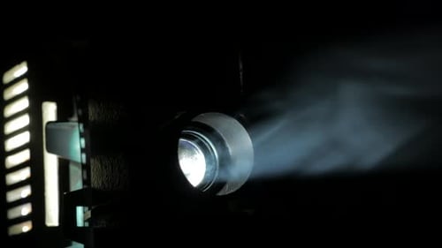 Old Film Projector Lens Playing in the Smoky Dark Room. Close Up.