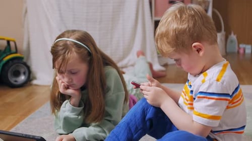 Children using tablet and phone inside home