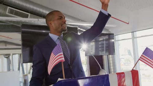 Man Giving Speech at Podium with American Flags
