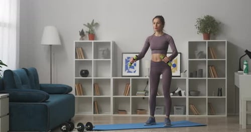 Hermosa mujer está entrenando con mancuernas en casa cuidando la salud y la buena condición física