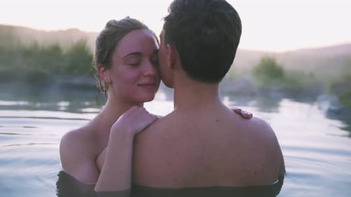 Casal feliz apaixonado tomando banho e relaxando na piscina quente na paisagem selvagem