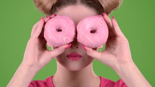 Girl Holds Two Donuts in Her Hands and Closes Her Eyes. Green Screen. Close Up