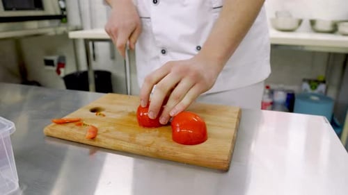 Chef Slicing Tomato with Precision in Kitchen