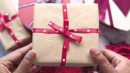 Top View of Man's Hand Holding a Gift Box on Table