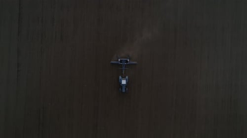 The tractor plows in the field. The camera flies over the tractor 07