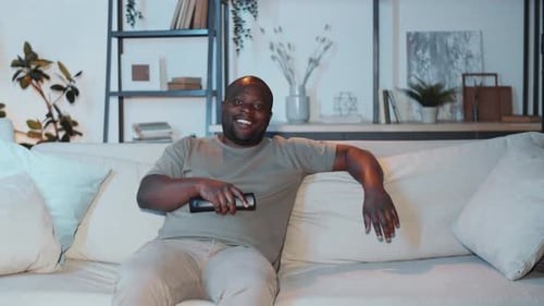 Smiling Man Relaxing on Couch with Remote
