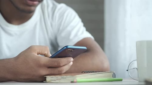Young Adult Using Smartphone Indoors at Table
