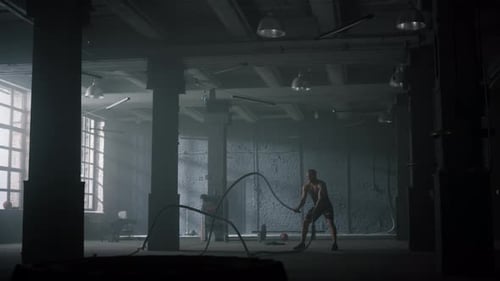 Guy Battling Ropes in Gym