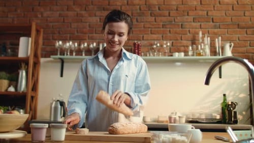 Woman Slices Baguette in Sunny Kitchen