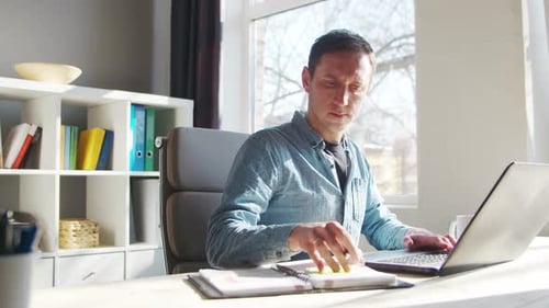 Young male entrepreneur works at home office at the computer.