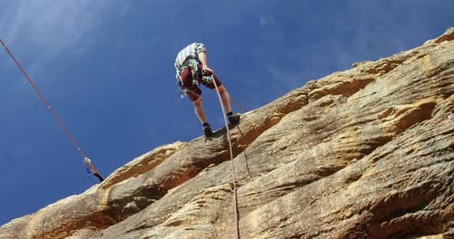 Mountaineer rappelling down the hill with the help of rope