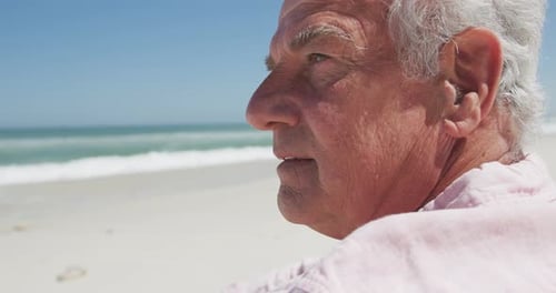 Nahaufnahme eines nachdenklichen älteren kaukasischen Mannes, der am Strand sitzt