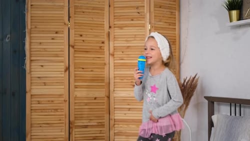 Energetic Girl Sings and Dances with Toy Microphone