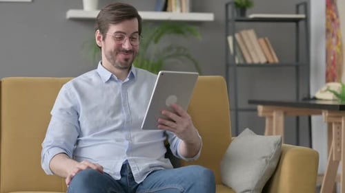 Cheerful Man Video Calling on Tablet Indoors