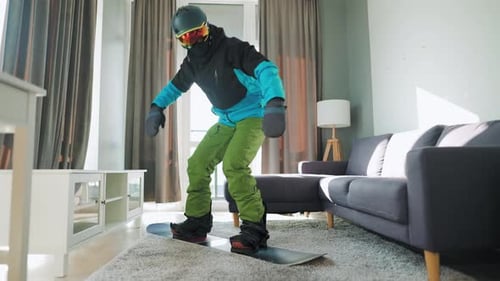 Vidéo amusante. Un homme déguisé en snowboardeur fait du snowboard sur un tapis dans une pièce confortable. En attente d'une
