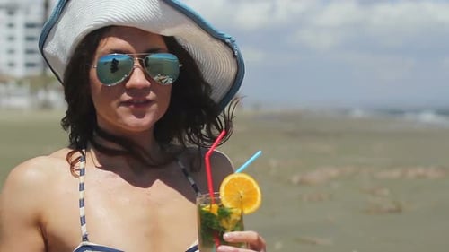 Closeup Beautiful Woman Wearing Sunglasses and Hat, Having Long Drink on Beach