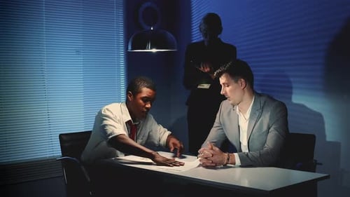 Two Men in Office Meeting Under Dim Light